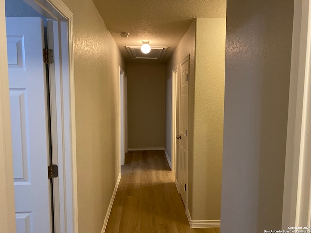 hallway with light hardwood / wood-style flooring and a textured ceiling