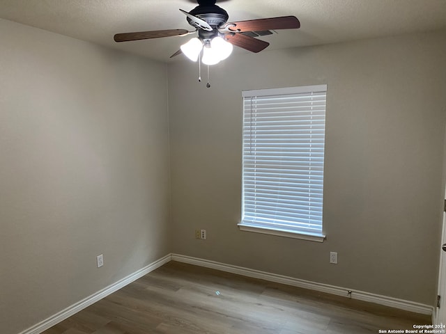 unfurnished room featuring ceiling fan, a textured ceiling, plenty of natural light, and hardwood / wood-style floors