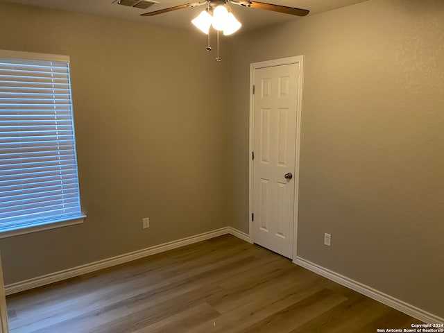 unfurnished room with a wealth of natural light, wood-type flooring, and ceiling fan