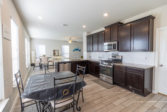 kitchen featuring appliances with stainless steel finishes, dark brown cabinetry, sink, ceiling fan, and light hardwood / wood-style flooring