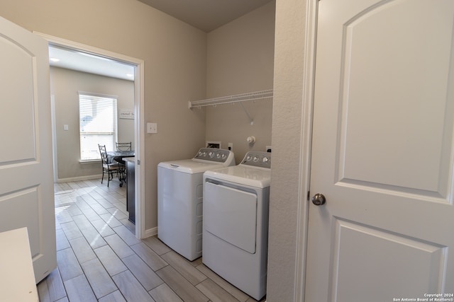 laundry room with light hardwood / wood-style flooring and washing machine and clothes dryer