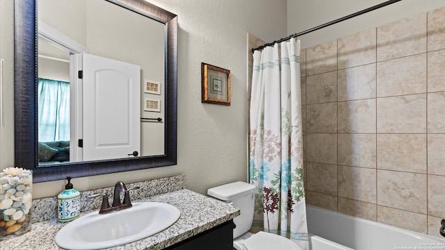 full bathroom featuring vanity, shower / bath combo with shower curtain, and toilet