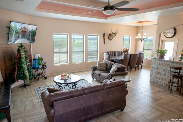 living room with light parquet flooring, a tray ceiling, and ceiling fan with notable chandelier