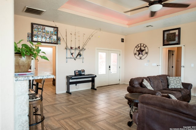 living room featuring french doors, a tray ceiling, parquet floors, and ceiling fan