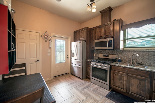 kitchen with dark brown cabinets, stainless steel appliances, backsplash, sink, and light parquet flooring