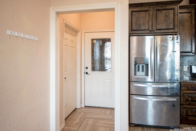 kitchen featuring light parquet flooring, dark brown cabinets, dark stone counters, and stainless steel refrigerator with ice dispenser