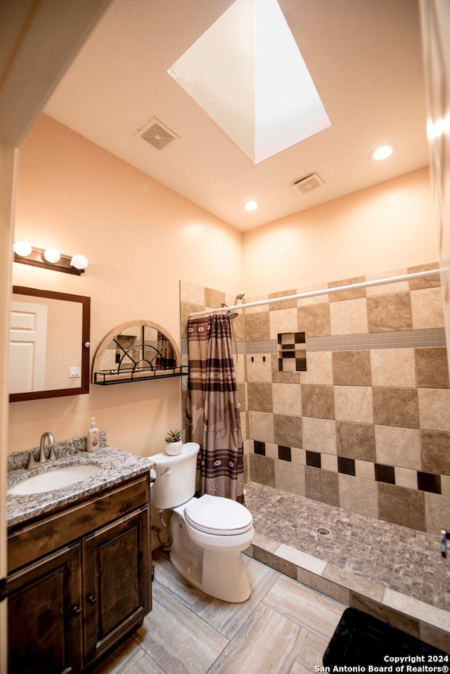 bathroom featuring toilet, a shower with curtain, vanity, tile walls, and a skylight