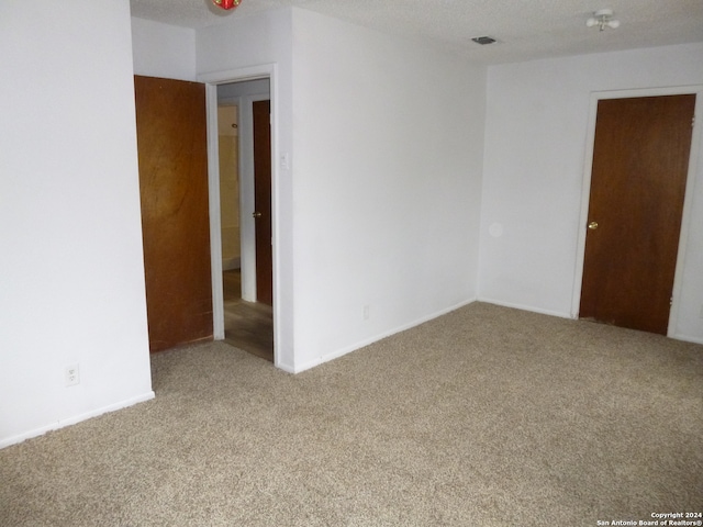 unfurnished room with carpet flooring and a textured ceiling