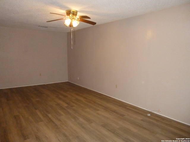 empty room featuring ceiling fan, dark wood-type flooring, and a textured ceiling