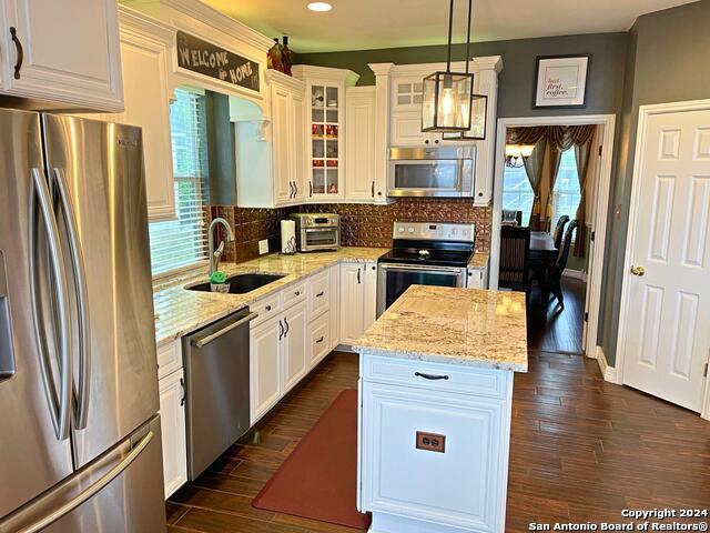 kitchen featuring stainless steel appliances, decorative light fixtures, dark hardwood / wood-style flooring, and white cabinets