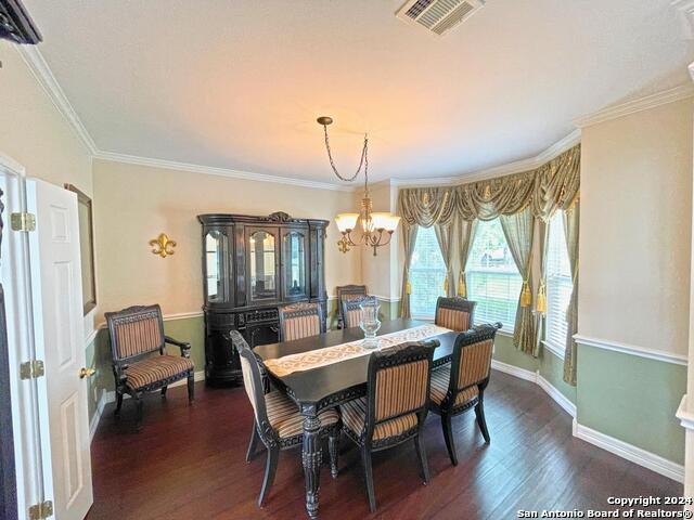 dining area featuring crown molding, an inviting chandelier, and dark hardwood / wood-style flooring