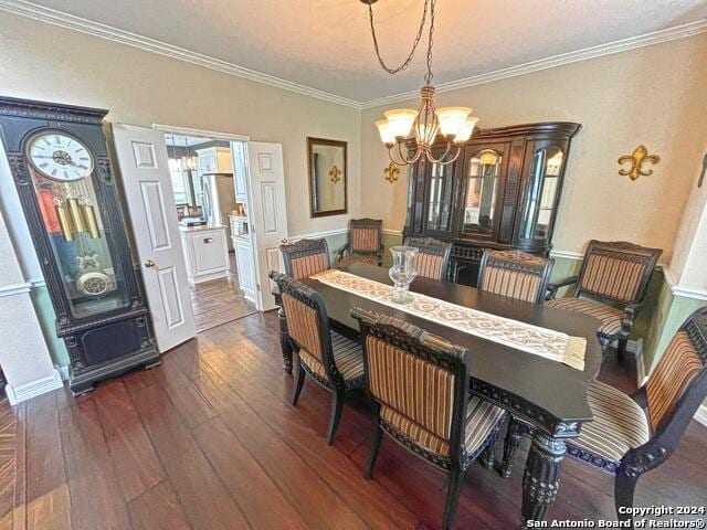 dining space featuring crown molding, a notable chandelier, and dark wood-type flooring