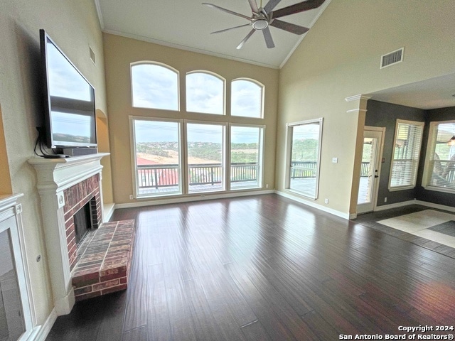 unfurnished living room with dark wood-type flooring, ornamental molding, a brick fireplace, high vaulted ceiling, and ceiling fan