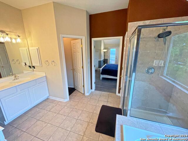 bathroom with a shower with door, tile patterned floors, and vanity