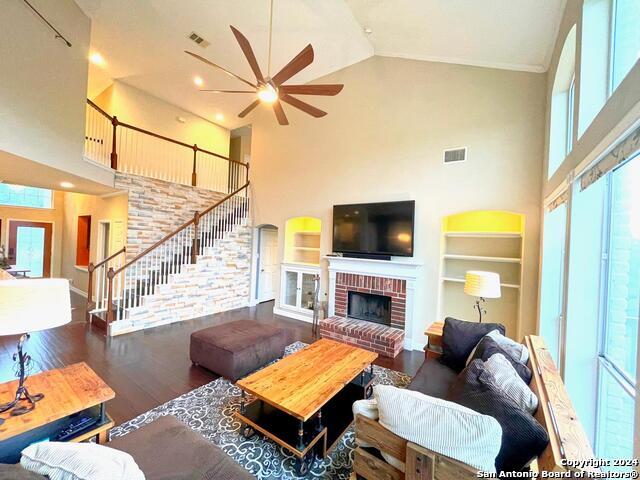 living room featuring ceiling fan, high vaulted ceiling, a brick fireplace, dark hardwood / wood-style floors, and built in shelves