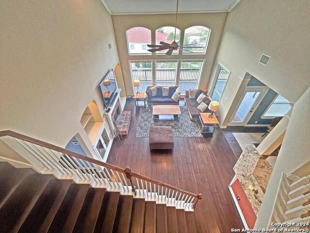 living room with a towering ceiling, dark hardwood / wood-style floors, and ceiling fan