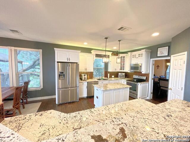 kitchen with a center island, stainless steel appliances, white cabinets, and tasteful backsplash