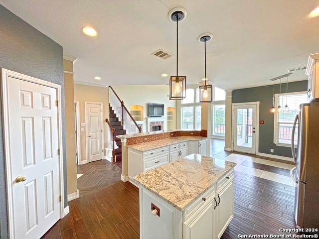 kitchen with dark hardwood / wood-style floors, stainless steel fridge, a center island, and pendant lighting