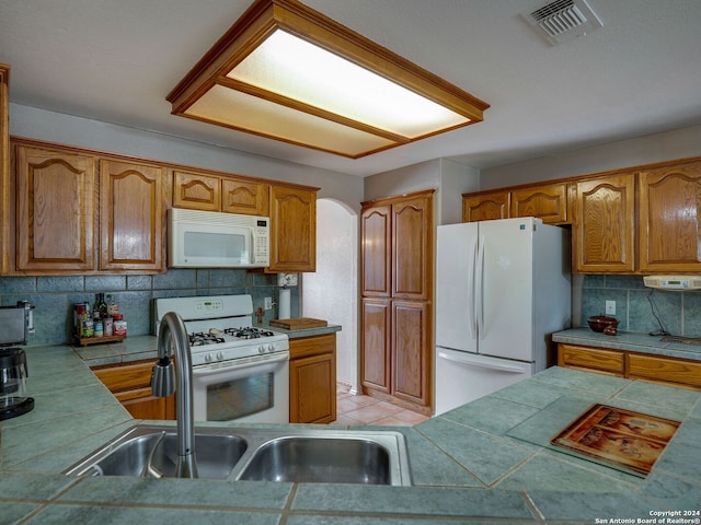 kitchen with tile counters, white appliances, and tasteful backsplash