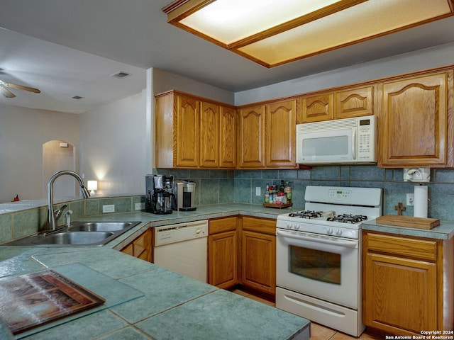 kitchen with kitchen peninsula, sink, tasteful backsplash, white appliances, and ceiling fan