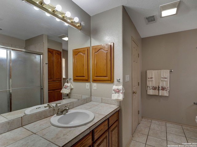 bathroom with vanity, a textured ceiling, tile patterned floors, and a shower with door