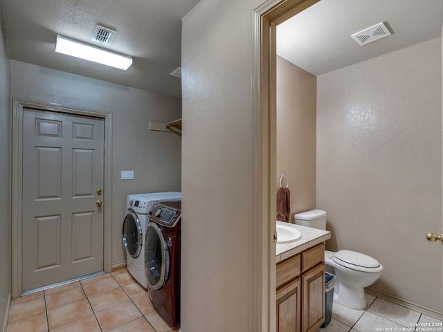 laundry room with sink, washing machine and dryer, a textured ceiling, and light tile patterned floors