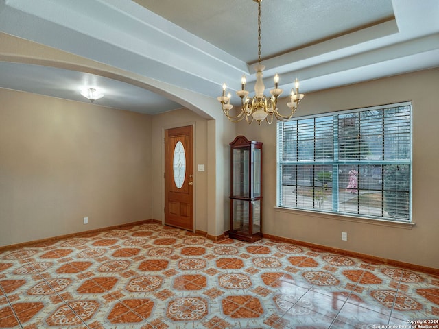 entrance foyer with a notable chandelier, light tile patterned floors, and a raised ceiling