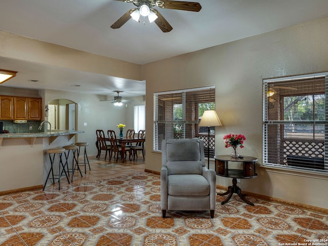 sitting room featuring sink, ceiling fan, a healthy amount of sunlight, and light tile patterned floors