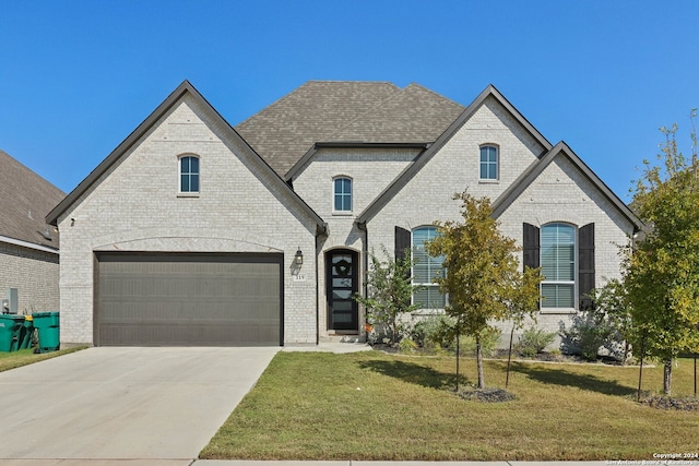 french country style house featuring a front yard and a garage