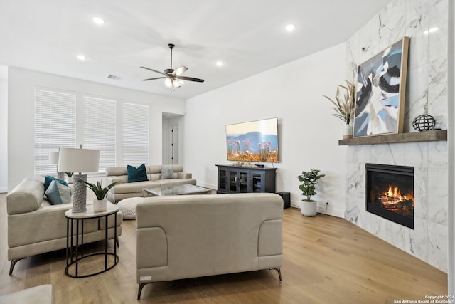 living room with ceiling fan, a premium fireplace, and light wood-type flooring