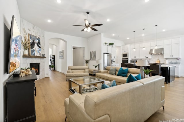 living room with light hardwood / wood-style floors, a premium fireplace, sink, and ceiling fan