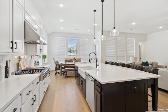 kitchen featuring a kitchen island with sink, light hardwood / wood-style flooring, a breakfast bar, white cabinetry, and appliances with stainless steel finishes