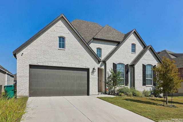 french country inspired facade with a front yard and a garage