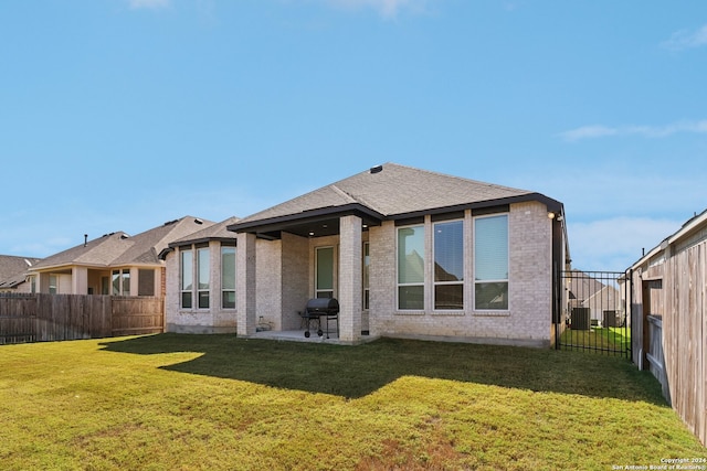 rear view of house featuring a patio area, central AC, and a lawn