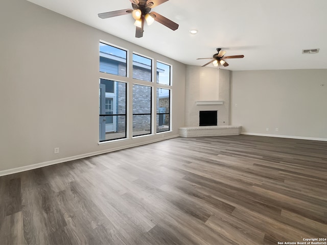 unfurnished living room with ceiling fan, a fireplace, and dark hardwood / wood-style floors