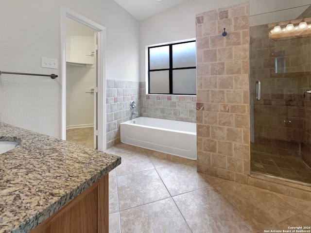 bathroom with shower with separate bathtub, tile patterned floors, vaulted ceiling, tile walls, and vanity