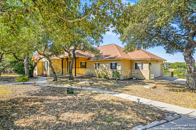 view of front of house featuring an attached garage, stone siding, driveway, and stucco siding