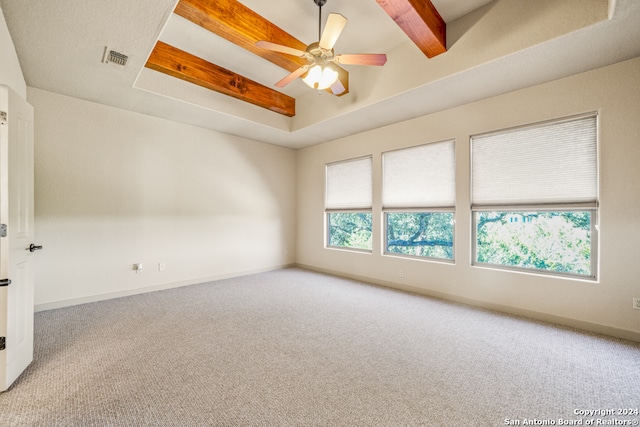 carpeted spare room featuring beam ceiling, a raised ceiling, visible vents, ceiling fan, and baseboards