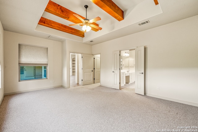 unfurnished bedroom with connected bathroom, light carpet, a tray ceiling, and ceiling fan