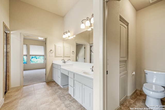 bathroom with baseboards, a sink, toilet, and double vanity