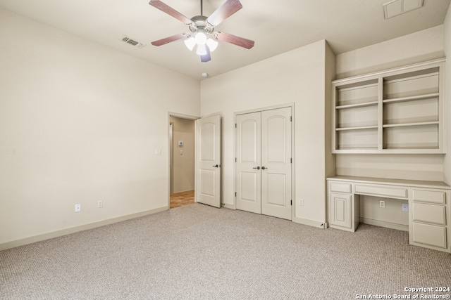 unfurnished bedroom featuring light carpet, baseboards, visible vents, and built in desk