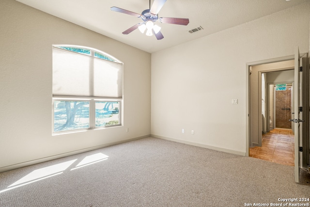 carpeted empty room with baseboards, ceiling fan, visible vents, and a wealth of natural light