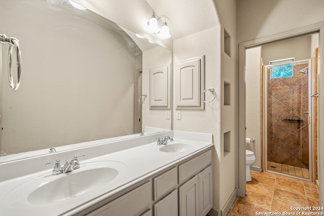 full bathroom with double vanity, a sink, toilet, and a shower stall