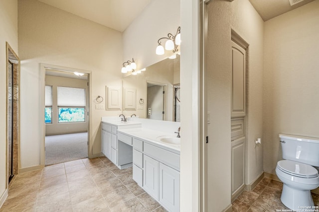 full bathroom featuring toilet, double vanity, baseboards, and a sink