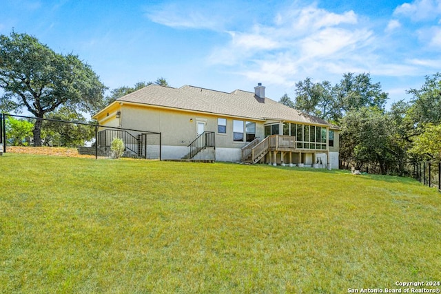 back of house featuring a yard, a chimney, fence, and a sunroom