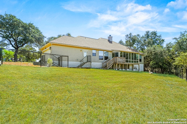 rear view of property featuring a lawn and a sunroom