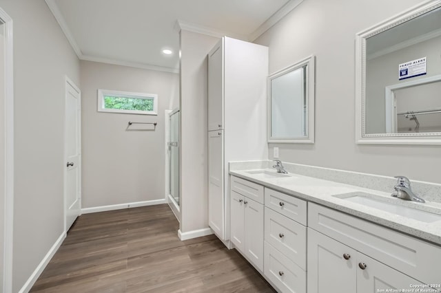 full bathroom with ornamental molding, a shower stall, double vanity, wood finished floors, and baseboards