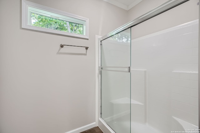 bathroom with crown molding and a shower with shower door