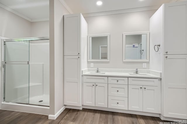 bathroom featuring crown molding, a shower stall, wood finished floors, and double vanity