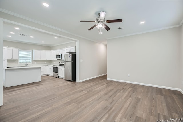 kitchen featuring appliances with stainless steel finishes, open floor plan, a ceiling fan, a sink, and light wood-style floors